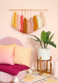 a bedroom with pink walls and colorful pillows on the bed, along with hanging tassels