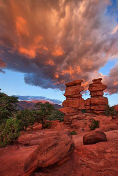 some rocks and trees under a cloudy sky with clouds in the backgrouds