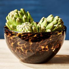 a bowl filled with green flowers sitting on top of a wooden table