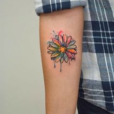 a woman's arm with a colorful flower tattoo on the left side of her arm