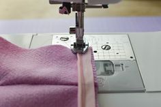 a close up of a sewing machine with pink fabric