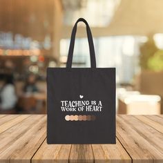 Start the conversation with this cute and practical tote bag! Our diverse teacher tote bag in black is perfect for carrying books, supplies, and essentials. It exudes a professional yet casual vibe, making it suitable for teachers, educators, and anyone who values diversity and inclusion. Ideal for back-to-school season, teacher appreciation week, and everyday use! Product features - Made from 100% cotton canvas for strength and durability - Features flat corners for a sleek look - Equipped with carrying handles for easy transport - Constructed with heavy 12 oz/yd² fabric for longevity - Available in black color Care instructions - Do not iron directly over the printed area - print may stick to the iron. - Spot clean - Do not bleach - Line dry Teacher Tote Bag, Teacher Bag, Diversity And Inclusion, Teacher Bags, Teacher Tote, School Season, Teacher Appreciation Week, Gifts For Teachers, Color Care