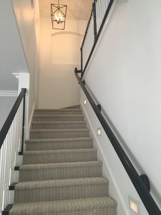 a staircase with carpeted steps leading up to a light fixture hanging from the ceiling