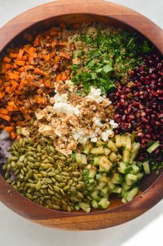 a wooden bowl filled with lots of different types of vegetables and seasonings on top of each other