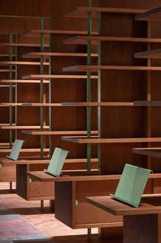 rows of wooden bookshelves in a library with green book ends on each shelf