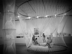 two people sitting in a white hammock with lights strung across the top and bottom