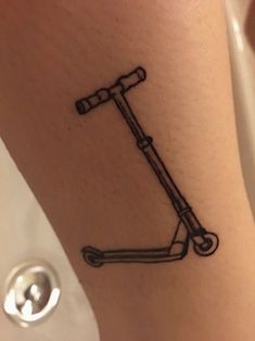 a small scooter tattoo on the leg that is black and white in color