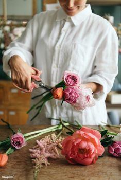 a person cutting flowers with scissors on a table