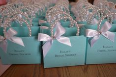 small blue boxes with pearls and bows on them are sitting on a table in front of other boxes