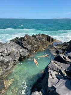 two people diving into the ocean from rocks