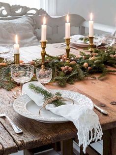 a wooden table topped with plates and candles