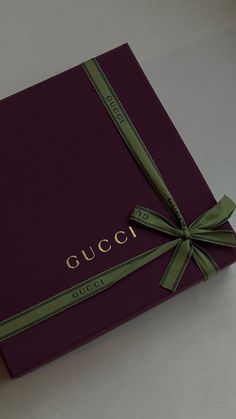 a purple gucci box with a green ribbon tied around it