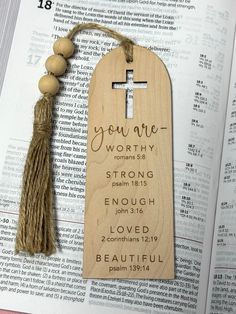 a wooden bookmark with a cross and tassel on top of an open bible