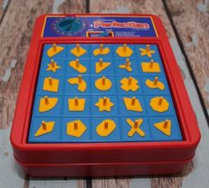 a red and blue children's toy with yellow plastic shapes on it sitting on a wooden surface