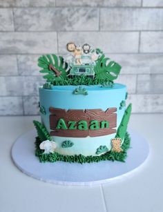 a blue cake with green grass and animals on the top that says azan in large letters