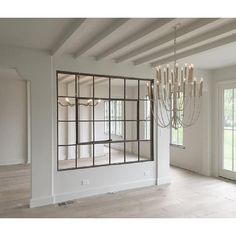 an empty room with a chandelier and large mirror in the center, surrounded by windows