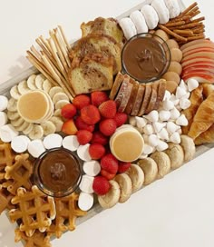 a platter filled with lots of different types of food and pretzel sticks