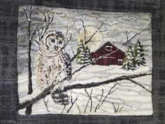 an owl is perched on a tree branch in the snow with a barn in the background