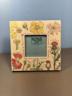 an old photo frame with flowers painted on the front and sides, sitting on a table