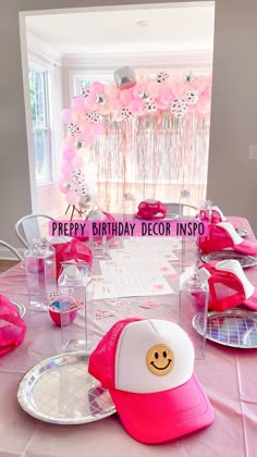 the table is set up with pink and white plates, hats, and balloons on it