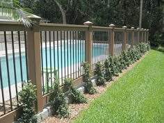 a fenced in swimming pool next to a lush green lawn