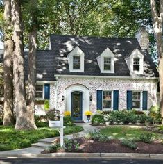 a white brick house with blue shutters on the front and side windows, surrounded by trees