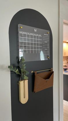 a wall mounted magnetic calendar with a plant in a vase on the door way to an office