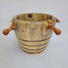 a wooden bowl with two handles and three birds on the handle, sitting on a white surface