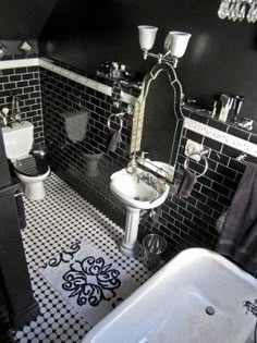 a bathroom with black and white tiled walls, flooring, and bathtub in it