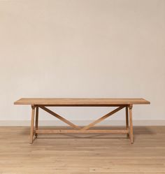 a wooden table sitting on top of a hard wood floor next to a white wall