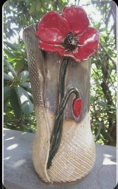 a ceramic vase with a red flower on it