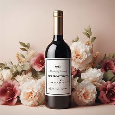 a bottle of wine sitting on top of a table next to pink and white flowers