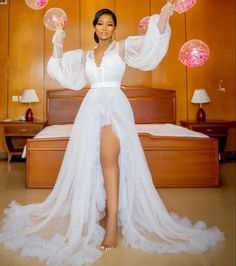 a woman in a white dress standing on a bed with bubbles floating from her hands