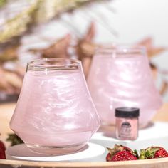 two pink candles sitting on top of a table next to strawberries