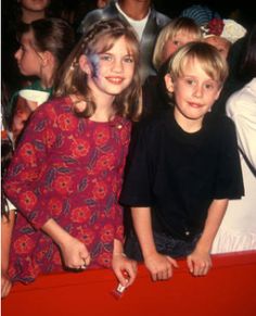 two young children standing next to each other in front of a large group of people