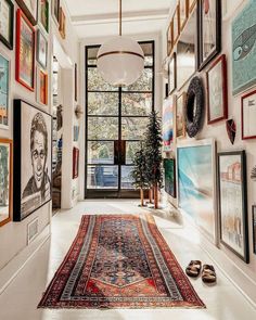 the hallway is decorated with many framed pictures and rugs on the floor, along with a potted plant