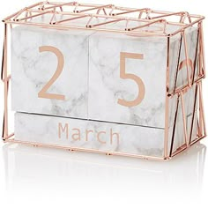 marble block calendar with rose gold numbers and the date march 25 on it's side