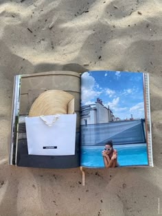 an open book on the sand with a woman taking a photo in front of it