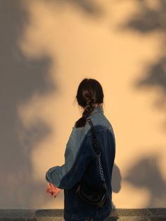 a woman sitting on the edge of a wall with her back turned to the camera