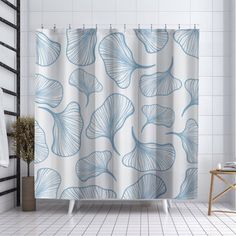 a blue and white shower curtain with leaves on it in a bathroom next to a bathtub