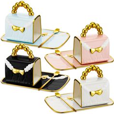 four different colored boxes with gold handles and bows on the top, one has a black purse