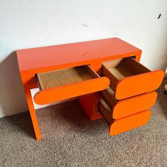 an orange desk with drawers on the bottom and one drawer open to show what's inside