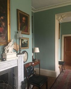 a living room with blue walls and paintings on the wall, a fireplace in the middle