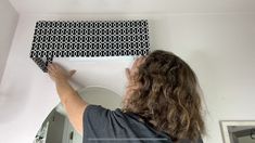 a woman is painting the wall with black and white patterns on it in her bathroom