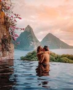 two people are sitting in the water next to each other and one person is kissing