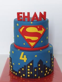 a superman cake with the name ehan on top and city lights in the background