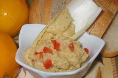 a bowl filled with food next to bread and oranges