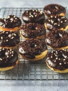 there are many chocolate donuts on the cooling rack