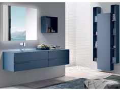 a modern bathroom with blue cabinets and white brick walls, along with a large mirror on the wall