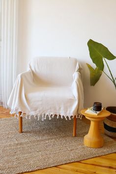 a white chair sitting on top of a wooden floor next to a potted plant